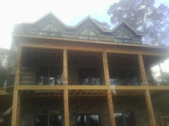 Dormers and porch framing on a large log home under construction — Roof Coating work by our crew in Zuni