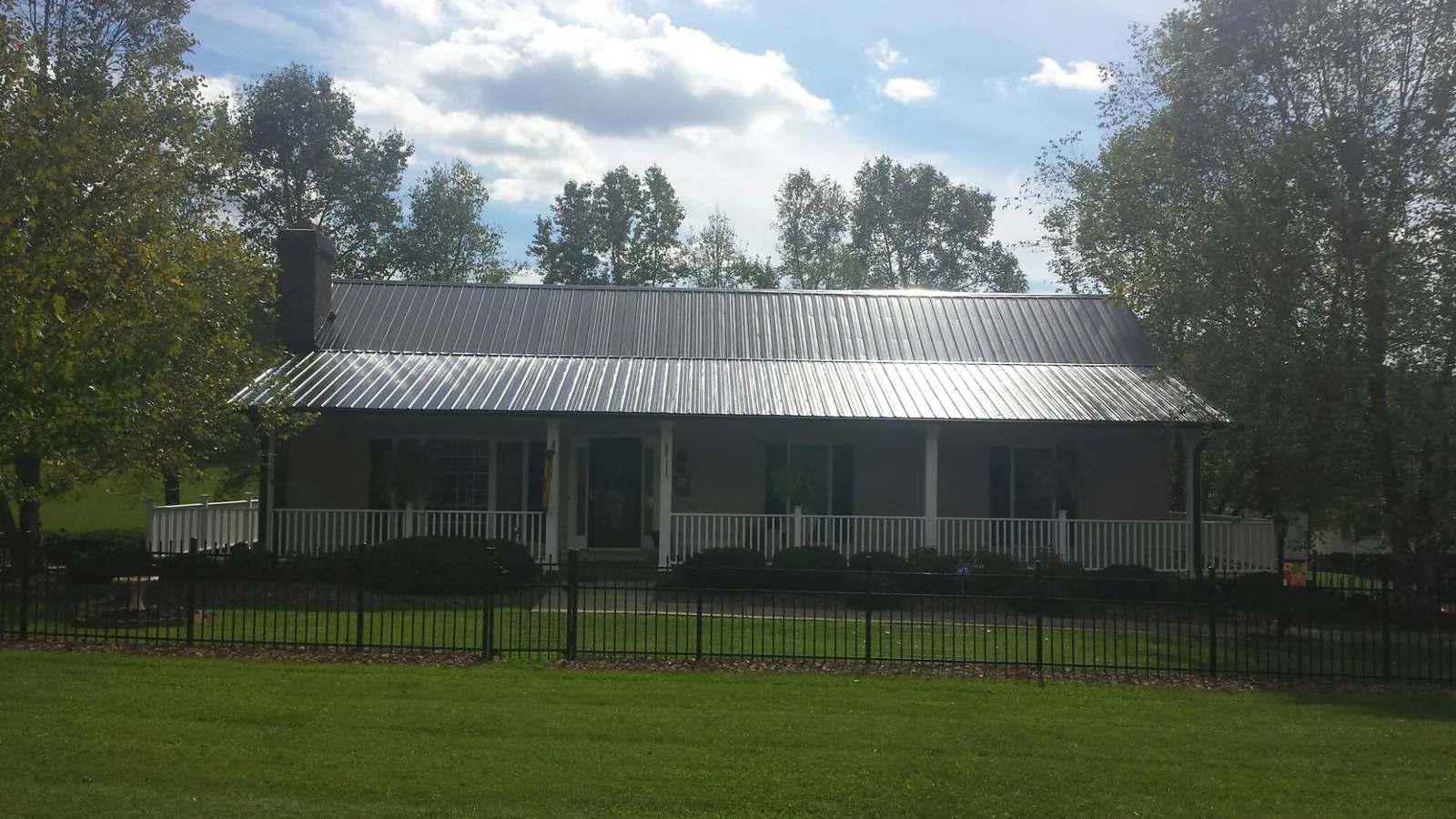 Gray metal roof on a brick ranch with a full width front porch — Gutter Guard Installation work by our crew in Zuni