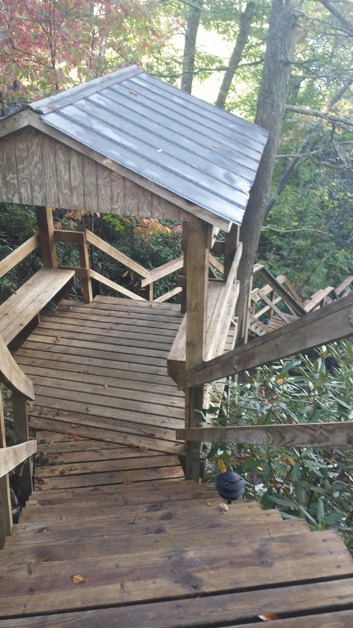 Metal roofed shelter over wooden steps on a wooded walkway — Skylight Repair & Installation work by our crew in Zuni