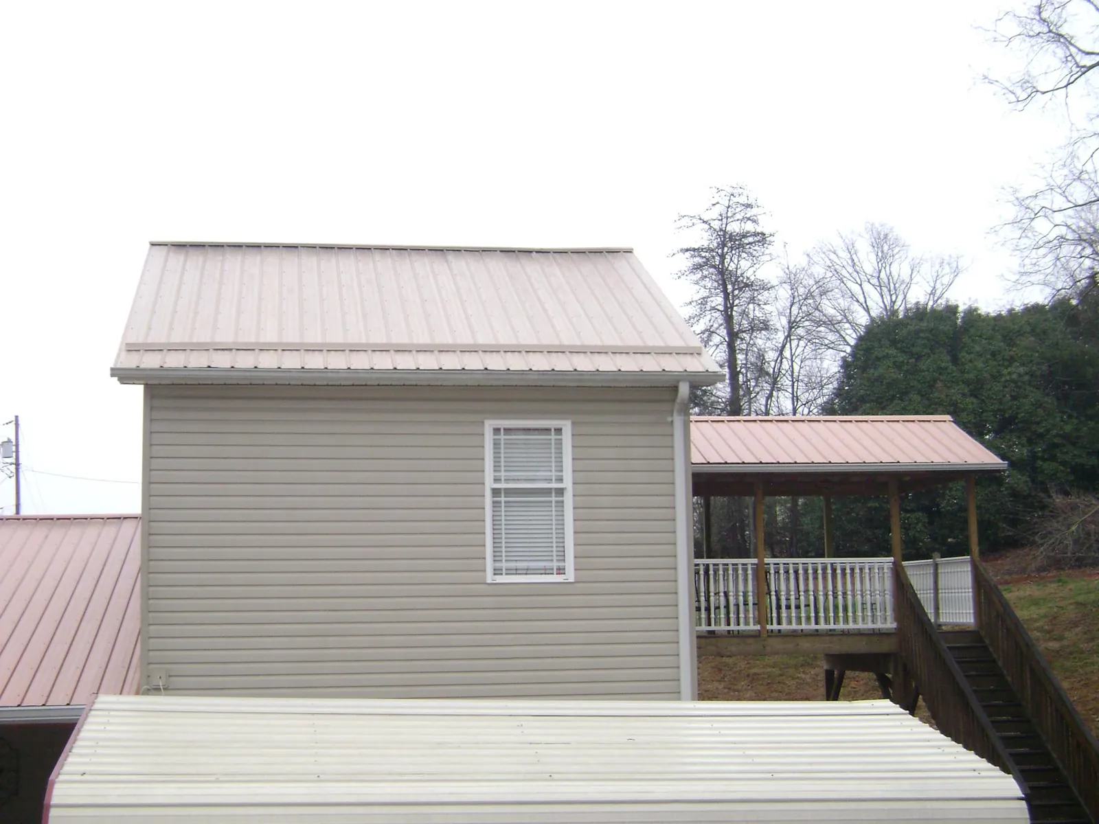 Tan metal roofs on a two story addition and attached porch, from a Roof Replacement job in Zuni