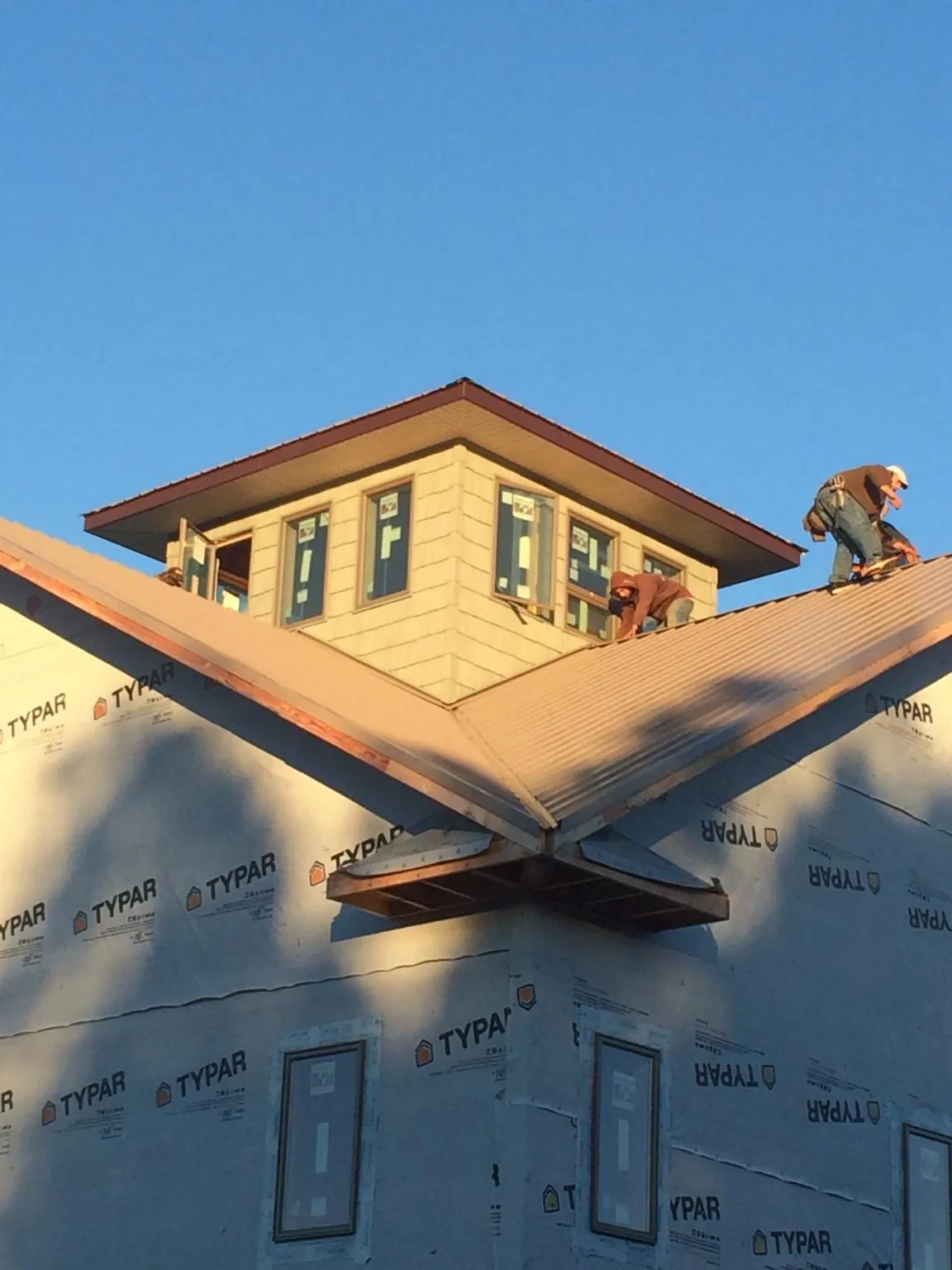 Roofers working around a rooftop cupola on a new metal roof at sunset — Roof Waterproofing in Zuni by Roofing Brothers